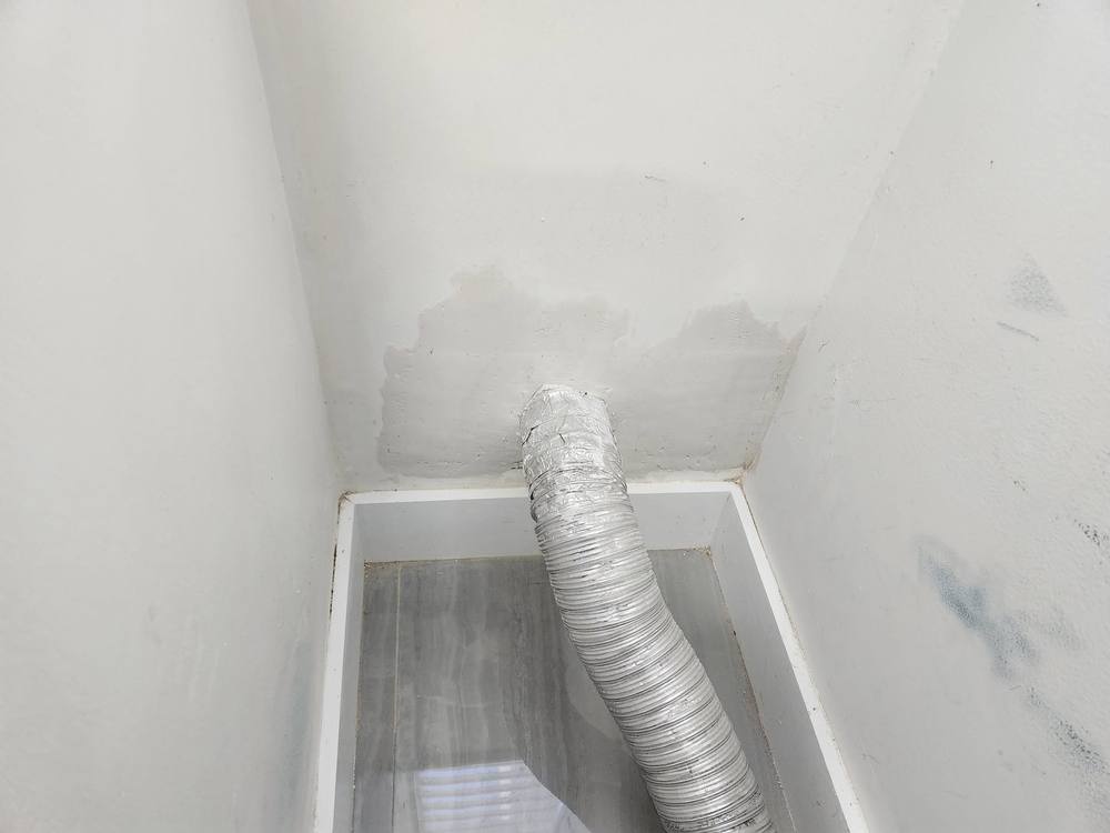 After: dryer vent reconnected with new foil duct and the wall patched smooth