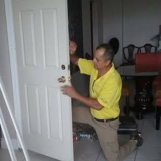 Mario kneeling to fit the hardware on a new white six-panel interior door